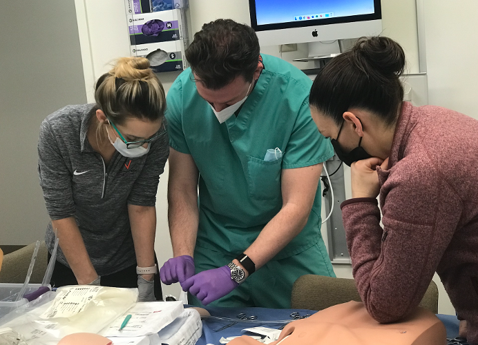 Two fellows receive training from an instructor